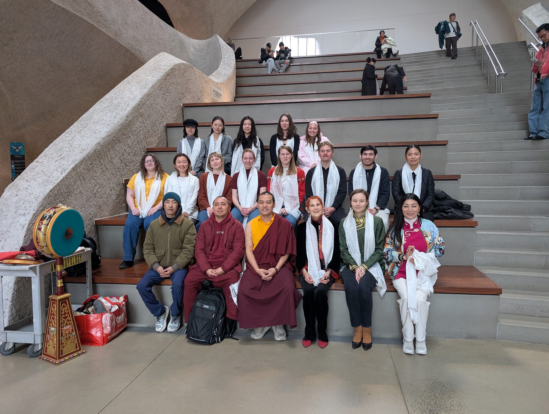 A group photograph of the Columbia Class of 2026 with Cham performers at the American Museum of Natural History.