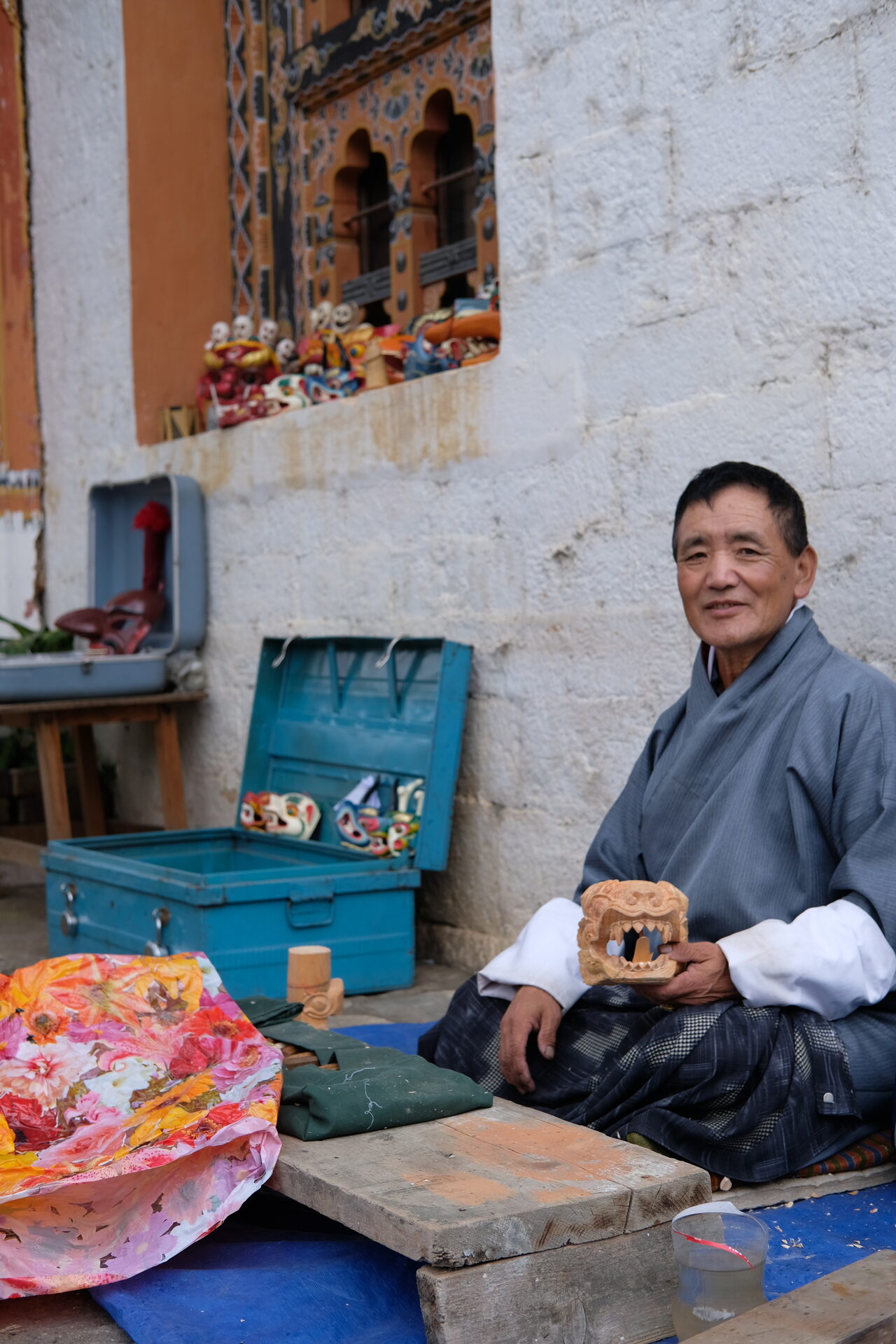 Chime Dorji, a mask carver in Thimphu, Bhutan, holding a wooden mask in his workshop.