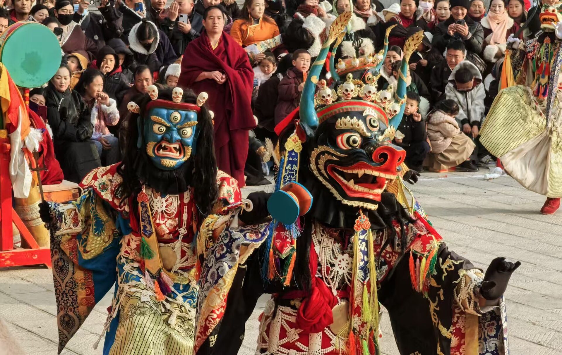 Shinje Shè and a wrathful Guru cross the courtyard of Lower Sengeshong Monastery during a New Year Cham ritual in Rebgong.